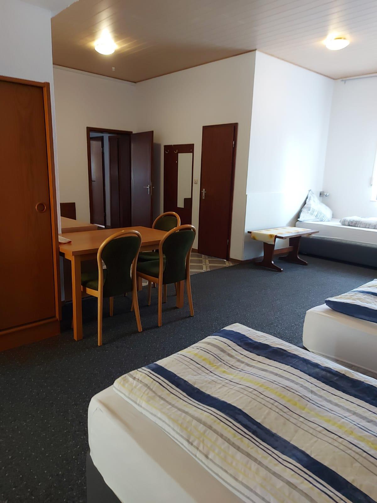 Multi-bed room with dining table and seating at Hotel Weller Mühlheim am Main